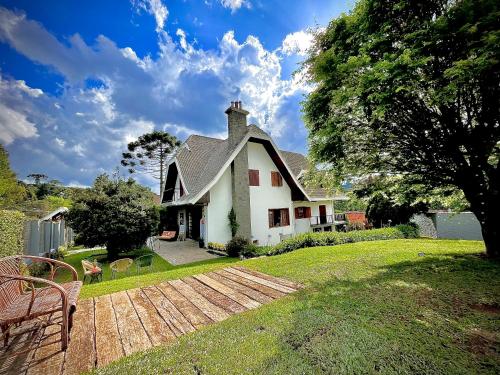a white house with a yard with a wooden deck at Casa Três Rios - Campos do Jordão in Campos do Jordão