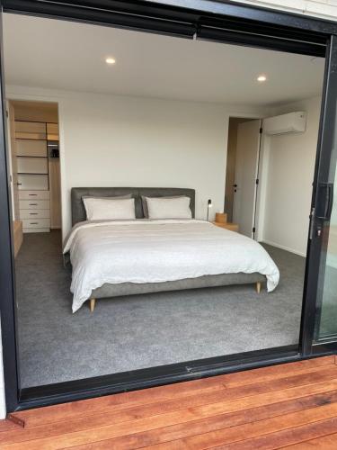 a bedroom with a bed with a large glass window at Luxury at the Lake in Hamilton
