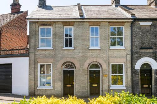 a brick house with black doors and white windows at Unique city centre house with log burner & courtyard in Norwich