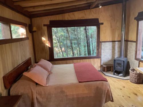 a bedroom with a bed and a window and a stove at Cabañas Lickanantay in Puerto Varas