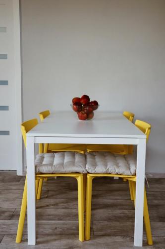 a white table with yellow chairs and a bowl of fruit at Apartamenty Wilga spokojne miejsce z całorocznym jacuzzi i letnim basenem in Wilga