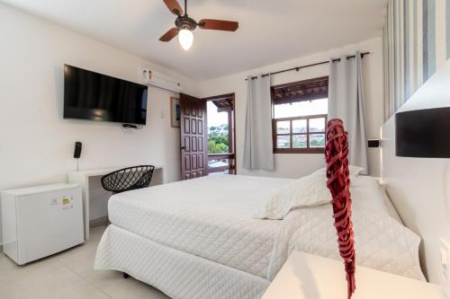 a bedroom with a white bed and a flat screen tv at Pousada do Timoneiro in Arraial do Cabo