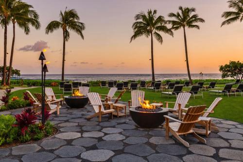 a patio with chairs and palm trees and the ocean at Koa Kea Resort on Poipu Beach in Koloa