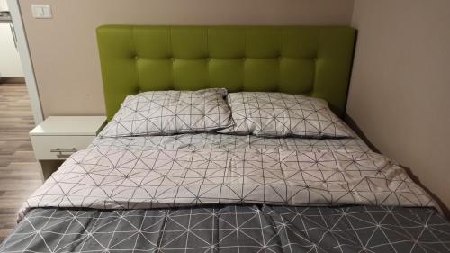 a bed with a green headboard and two pillows at Cozy home Bujorilor in Timişoara