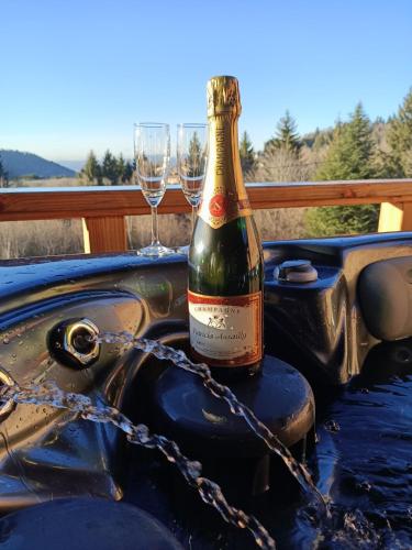 a bottle of champagne sitting on a table with two wine glasses at Chalet neuf avec jacuzzi privé, vue imprenable sur Massif des Vosges in Belfahy