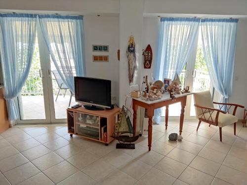een woonkamer met een tv en een tafel met een televisie bij Alpha apartment, Ireon Samos in Iraion