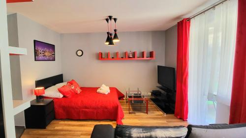 - un salon avec un lit rouge et une télévision dans l'établissement APARTMENT LUXURY OASIS Śródmieście DOWNTOWN 3 os, à Cracovie