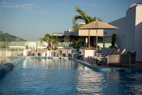 a swimming pool with chairs and an umbrella at New & Equipped Apartment Steps From The Beach With Pool Jacuzzi By Yeah in Playa del Carmen
