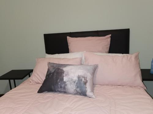 a bed with pink pillows and a black headboard at A home away from home in Nelspruit