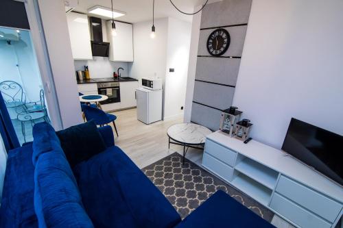 a living room with a blue couch and a kitchen at Apartament SHARK w centrum z klimą in Iława
