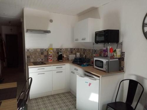 une petite cuisine avec des armoires blanches et un micro-ondes dans l'établissement Appartement au cœur de la ville, à Ax-les-Thermes