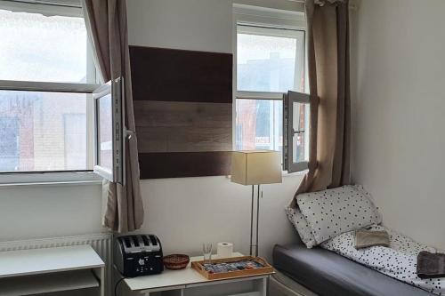 a small room with a bed and two windows at Spacious bedroom close to city centre in Sheffield