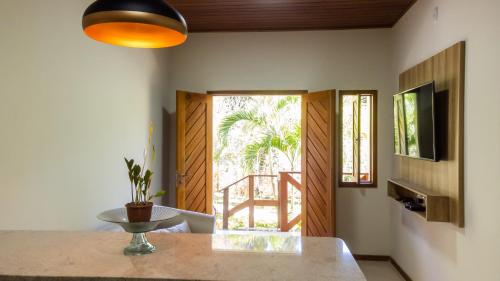 a dining room with a table and a large window at Flats Brasil Itacaré in Itacaré