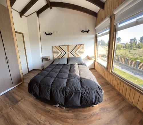 1 dormitorio con 1 cama grande en una habitación con ventanas en Cabaña Pilpilen - Curaquilla Lodge "Entre humedales y el Mar", en Arauco