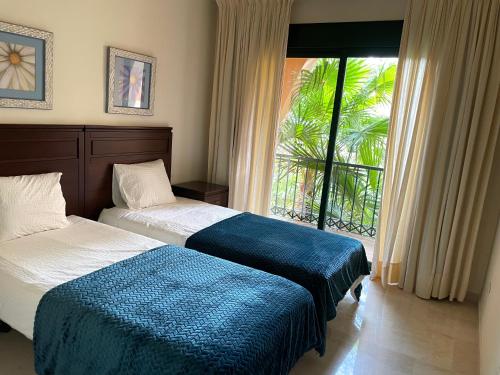 een slaapkamer met 2 bedden en een groot raam bij Apartment next to the El Campanario, Atalaya Golf in Estepona