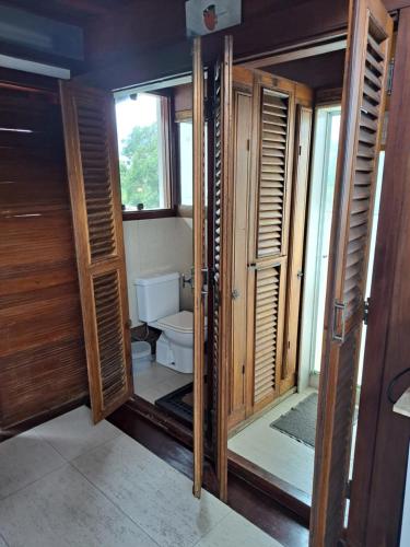 a bathroom with a toilet and some wooden doors at Loft Verde Chic na Barra da Tijuca in Rio de Janeiro