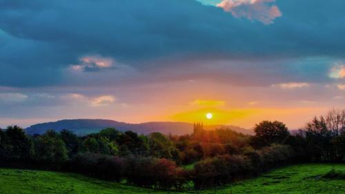 a sunset over a field with the sun in the sky at Casa Merle in Westouter