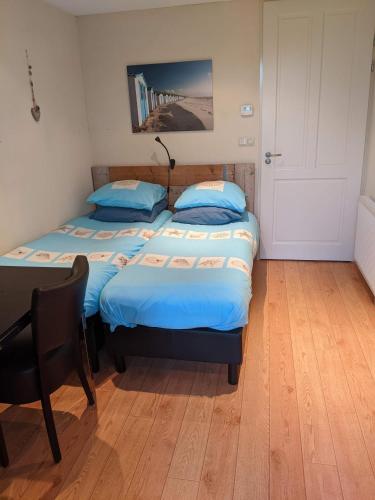 two beds in a room with a desk and a table at Logies21 Texel in Oosterend