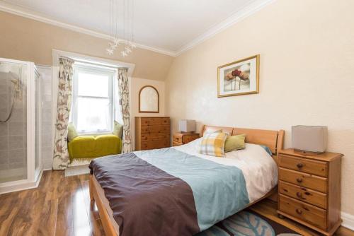 a bedroom with a bed and a dresser and a window at Abercorn Lodge Semi-Detached House in Edinburgh