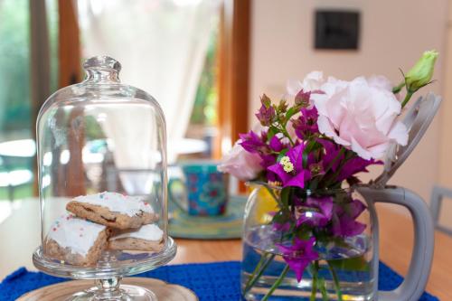 a glass jar with cookies and flowers in a vase at Villetta Alcumissa in San Teodoro