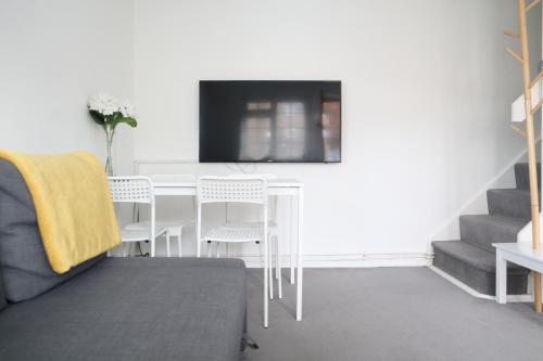 Il comprend un salon doté d'une table blanche et d'une télévision. dans l'établissement Twelve Thirty Serviced Apartments - Balham, à Londres