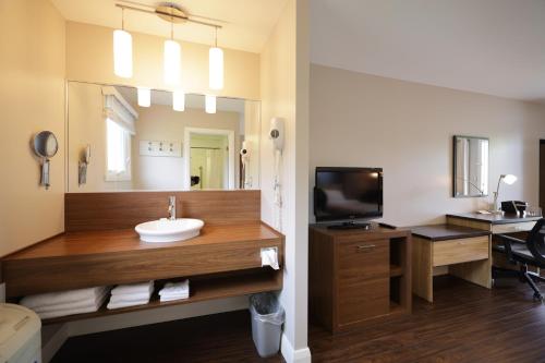 a bathroom with a sink and a mirror and a desk at Auberge de la Pointe in Rivière-du-Loup