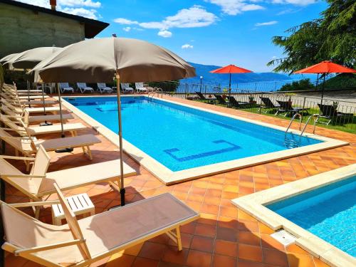 una piscina con tumbonas y sombrilla en Residence Casa Silvana, en Tignale