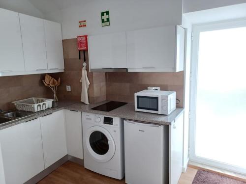 a kitchen with a washing machine and a microwave at Lugar de Santana in Sesimbra