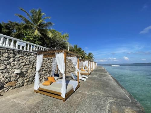 eine Reihe von Betten an einer Wand neben dem Wasser in der Unterkunft Hotel Cocoliso Island Resort in Isla Grande