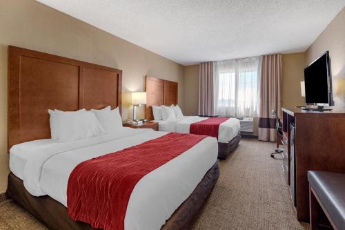 a hotel room with two beds and a flat screen tv at Comfort Inn & Suites Hays I-70 in Hays