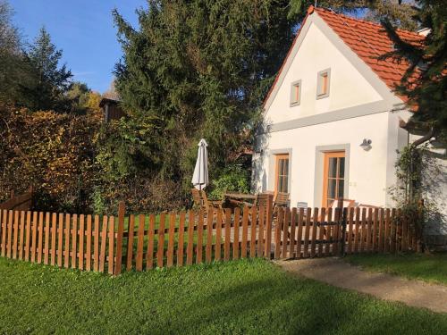 a white house with an umbrella and a fence at Apartmány Kojákovice - Třeboň in Jílovice