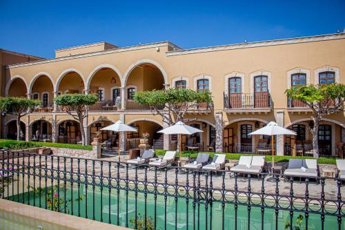a building with chairs and umbrellas next to a pool at HC HACIENDA CATRINA HOTEL BOUTIQUE in Silao