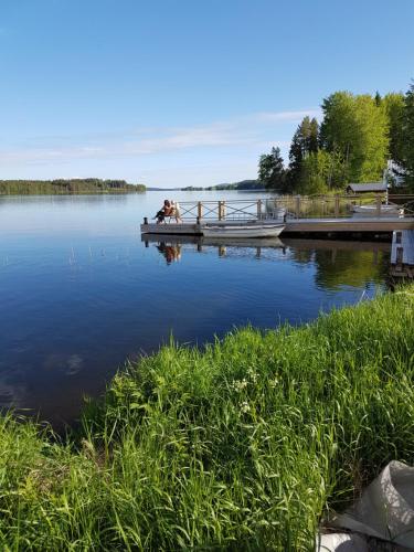 a couple of people sitting on a dock on a lake at Hugsnäset Semesterstugor och Fiske in Gällö