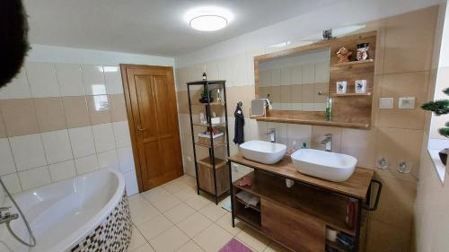 een badkamer met 2 wastafels, een bad en een bad bij My TALE apartment in Horná Lehota