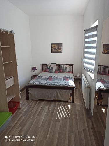 een slaapkamer met een bed en een houten vloer bij Le franco-belge in Wattrelos