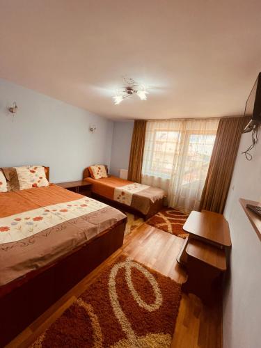 a hotel room with two beds and a window at Pensiunea Valea Ursului in Câmpulung
