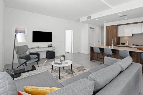 a living room with a gray couch and a kitchen at Level Los Angeles - Downtown Flower in Los Angeles