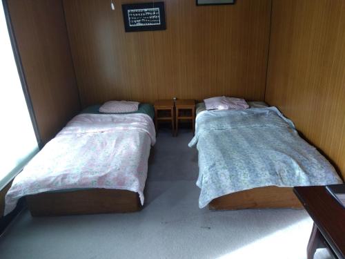 two twin beds in a small room with avertisement at Daramusara - Vacation STAY 13520 in Furano