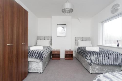 a bedroom with two beds and a window at Beech House Leeds in Leeds