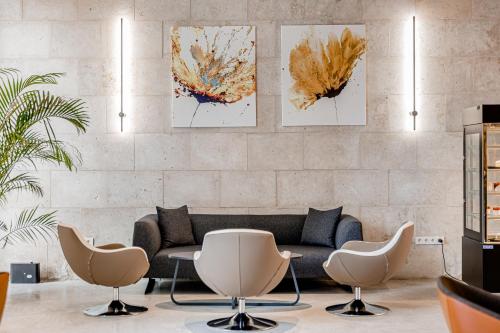 a living room with a couch and three paintings on the wall at Kutaisi Inn in Kutaisi