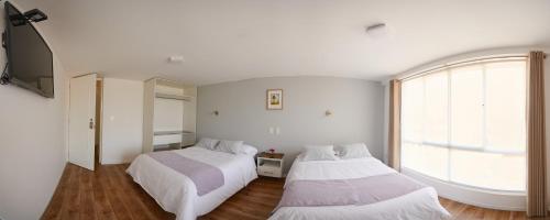 Duas camas num quarto com uma janela grande em Alma Casa Boutique em Arequipa