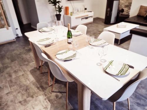 - une table blanche avec des chaises blanches et une bouteille de vin dans l'établissement La casa pétillante !, à Ay