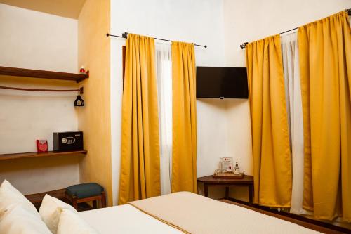 um quarto com cortinas amarelas e uma cama em Hotel con Corazón em Granada