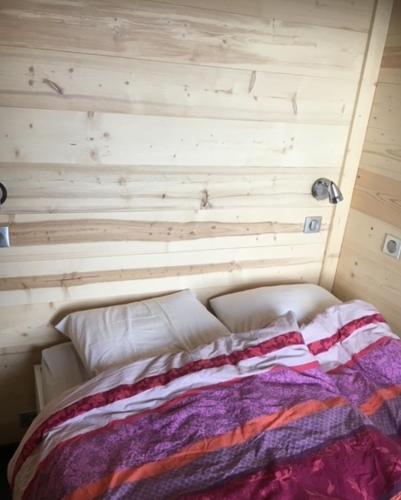 un lit dans une chambre avec un mur en bois dans l'établissement Appartement Velaer Valmorel, à Valmorel