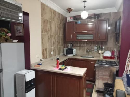 a small kitchen with wooden cabinets and a refrigerator at Blue Bay Asia Sokhna Aqua park بلو باي اسيا العين السخنه - عائلات فقط in Ain Sokhna