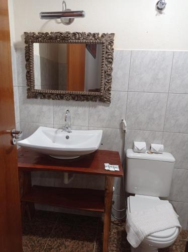 a bathroom with a sink and a toilet and a mirror at Brisa da Serra Hotel Pousada Pirenopolis in Pirenópolis