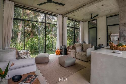 a living room with a couch and chairs and windows at Tao House Jungle Boutique Villas in Ahangama