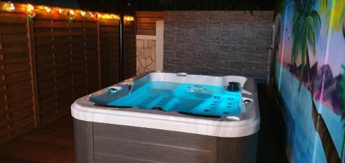 a bathroom with a blue tub in a room at "Chez Claudia "charmant logement avec jacuzzi privatif en toute intimité sur belle terrasse extérieure en bois et piscine in Courcelles Sucrerie