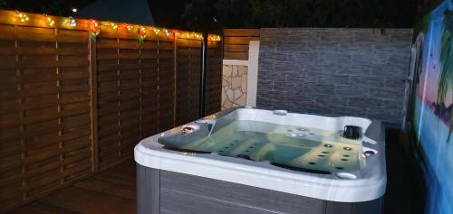 a jacuzzi tub in a backyard with lights at "Chez Claudia "charmant logement avec jacuzzi privatif en toute intimité sur belle terrasse extérieure en bois et piscine in Courcelles Sucrerie