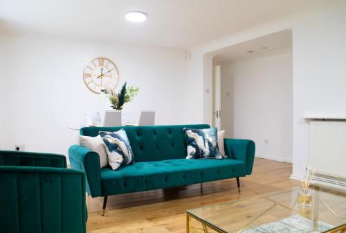 uma sala de estar com um sofá verde e um relógio em DELUXE Tranquil Central 2 Bedroom Home-Free Parking, WIFI, Garden Views, University of Birmingham, Botanical Gardens, Edgbaston cricket em Birmingham